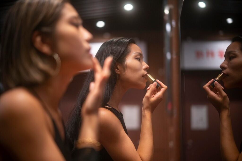 girls are applying lipstick inside the bathroom